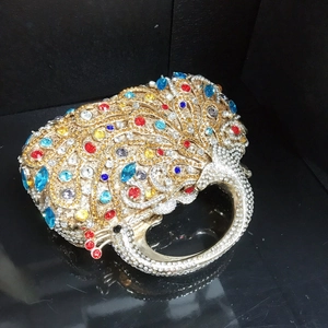 Détail macro d'une pochette de soirée paon en cristal avec strass colorés sur métal doré