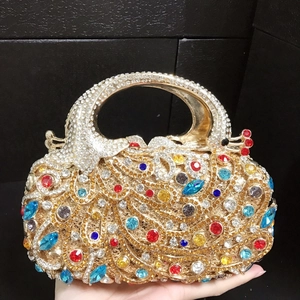 Détail d'un sac de soirée paon coloré avec strass scintillants et base dorée