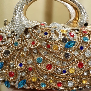 Détail de la pochette de soirée phénix colorée avec plumes en strass et poignée dorée chic