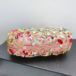 Détail macro du motif paon orné de cristaux et strass colorés sur une pochette de luxe