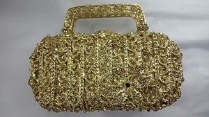 Détail d'un sac de soirée doré avec libellule en strass et motifs filigranes ajourés