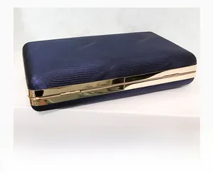 Detail of dark blue evening clutch featuring wavy texture and gold metal frame edges