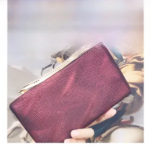 Macro shot of burgundy PU evening clutch showing wavy pleated texture and rhinestone clasp