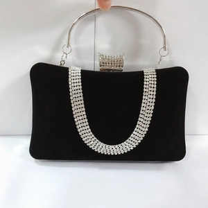 Close-up of black velvet evening clutch with silver U-shaped rhinestones and round handle
