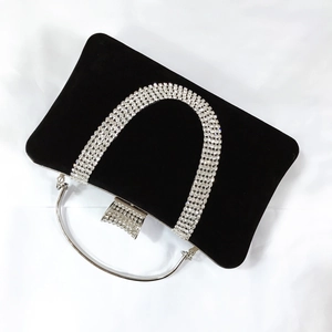 Close-up of black velvet evening bag featuring a U-shaped crystal trim and silver handle