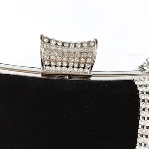 Macro detail of luxury black velvet evening bag with sparkling diamond-encrusted U-shape clasp