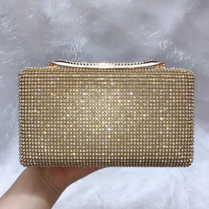 Dettaglio di pochette da sera dorata con strass incastonati e chiusura a scatto in metallo