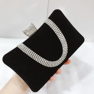 Close-up of sparkling U-shaped rhinestones and crystal clasp on black velvet clutch