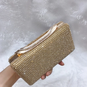 Dettaglio di borsa da sera dorata con strass scintillanti su sfondo di pelliccia bianca