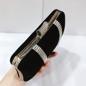Close-up of black velvet evening clutch featuring silver rhinestone bands and crystal clasp