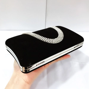 Detail of black velvet evening clutch featuring a shimmering U-shaped rhinestone pattern