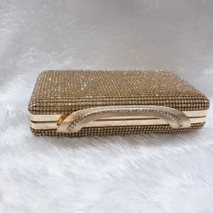 Dettaglio della borsa da sera dorata con strass scintillanti e manico decorato con gemme