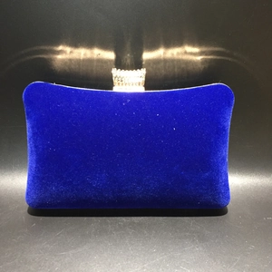 Close-up of royal blue velvet evening clutch with a sparkling gold crown clasp