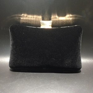 Close-up of black velvet evening bag featuring a gold crown clasp with sparkling rhinestones