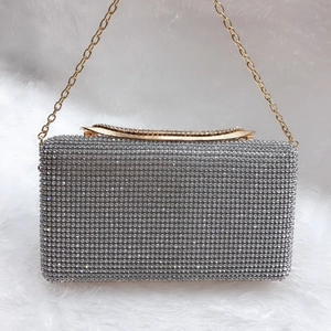 Dettaglio della pochette da sera con strass argento, manico in metallo oro e catena