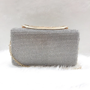 Dettaglio di pochette da sera con strass argento, manico in metallo dorato e catenella