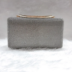 Clutch in strass argento con manico dorato su sfondo di ecopelliccia bianca