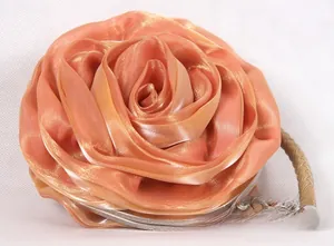 Close-up of peach silk rose evening bag with metallic frame and braided handle