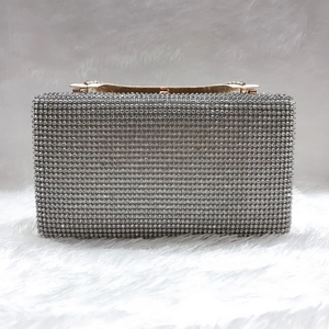Dettaglio della pochette da sera con strass argento, cornice dorata e cristalli lucidi