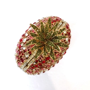 Close-up of sparkling pineapple evening bag with red crystals and green leaf clasp