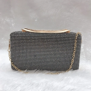 Dettaglio pochette con strass argento e cornice dorata su sfondo di pelliccia bianca