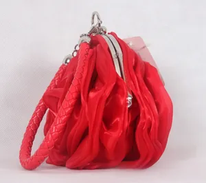Detailed side view of a red satin rose evening bag with silver clasp and woven handle