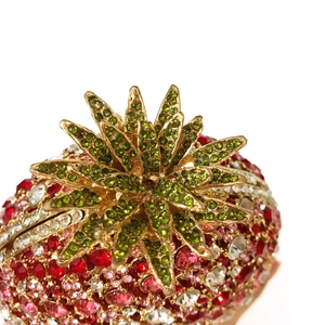 Detail of strawberry evening bag showing intricate multi-color rhinestone inlay and green leaves