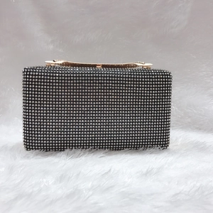 Dettaglio della pochette da sera con strass argento e chiusura in metallo dorato a onda