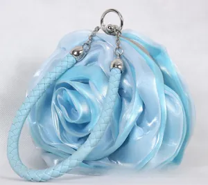 Detailed close-up of 3D light blue satin rose petal texture and woven handle of the evening bag