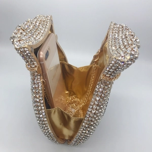 Makroaufnahme des Innenraums der High-Heel-Clutch mit Strasssteinen, Handy und Kette
