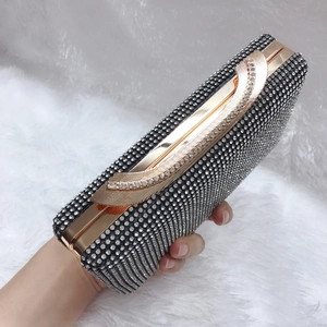 Dettaglio ravvicinato di una mano che tiene una borsa da sera nera con strass scintillanti