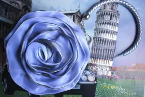 Close-up of a 3D purple satin rose evening bag with silver trim and metallic handle