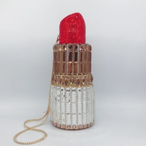 Detailed view of red and gold rhinestone lipstick shaped clutch with metal chain strap