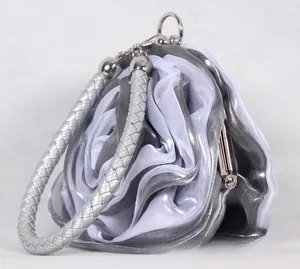 Detailed side view of 3D satin rose evening bag with grey-white petals and woven handle