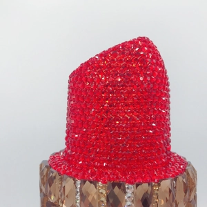 Macro detail of red rhinestone top and amber crystal base on luxury lipstick clutch