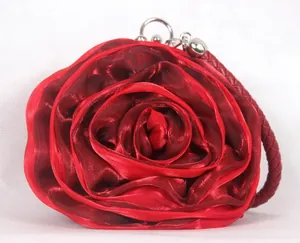 Macro view of red silk rose evening bag with layered petals and braided handle