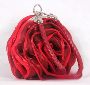 Detailed side view of a red silk rose evening bag with woven handle and metal clasp
