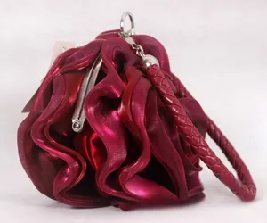 Macro shot of dark red rose-shaped evening bag with pleated silk petals and woven handle