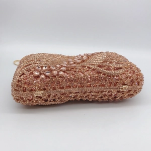Macro detail of rose gold evening clutch featuring rhinestone flower patterns and metal chain