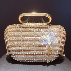 Détail d'un sac de soirée doré avec cristaux étincelants et une fleur en métal