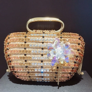 Détail de sac de soirée luxueux avec cristaux dorés, fleur en cristal et franges en métal