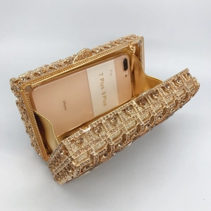 Luxurious gold crystal encrusted clutch bag featuring intricate hollow-out metal design