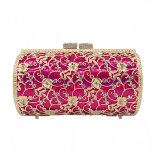 Detail view of the intricate hollow gold floral pattern and rhinestones on the rose pink clutch