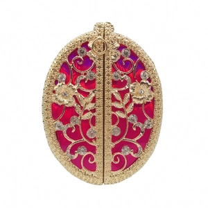 Macro detail of luxury gold floral engraving and red enamel on a crystal evening clutch bag