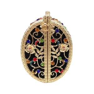 Close-up of golden hollow metal clutch bag featuring colorful rhinestones and floral pattern