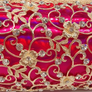 Macro detail of luxury evening bag with gold hollow floral pattern and sparkling rhinestones