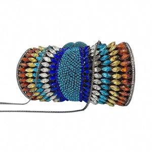 Close-up of colorful rhinestones on a cylindrical evening clutch bag with chain strap