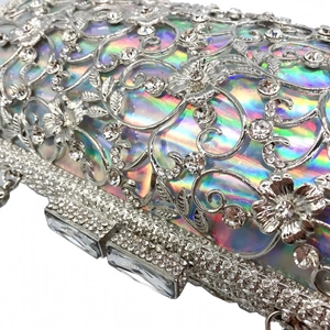 Macro detail of silver hollow floral metal clutch with rhinestones and iridescent lining