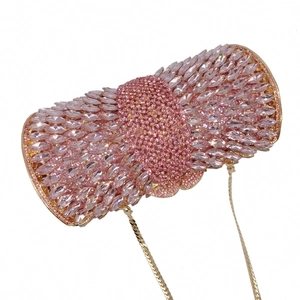Close-up of pink crystal bow-shaped evening bag with golden metal frame and chain
