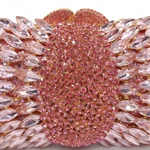 Macro detail of luxury evening bag with pink rhinestones and gold metal floral pattern